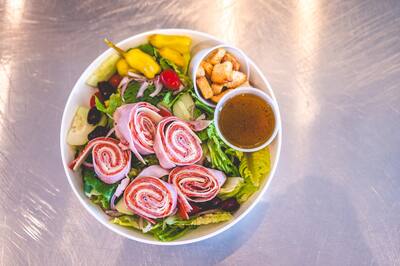 An antipasto salad with rolled meats, peppers and olives