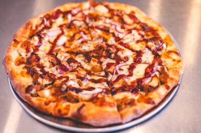 A BBQ Chicken pizza with red onion and a swirl of BBQ sauce