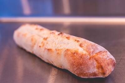 A loaf of Italian bread lying on a steel counter