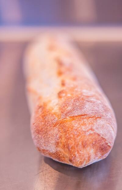 A loaf of Italian bread standing on a steel counter
