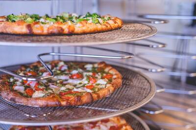 A pizza with broccoli on a tiered wire rack, close up