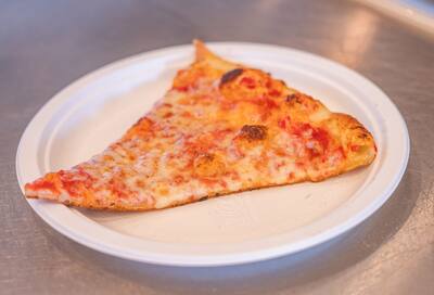 A cheese slice with a browned crust on a white paper plate