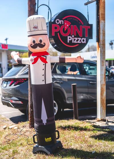 The inflatable chef standing by the road next to the On Point Pizza sign