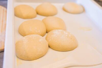 Balls of fresh pizza dough resting on a tray
