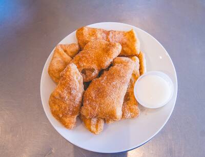 Cinnamon sugar dough boys on a white plate with a cup of white dip