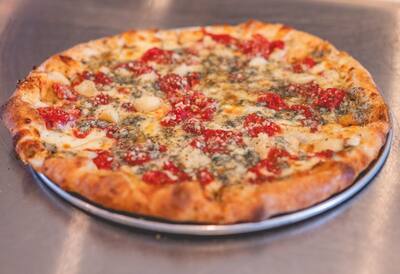 A Gorgonzola Special pizza with roasted garlic, tomato, gorgonzola and herbs on a round tray