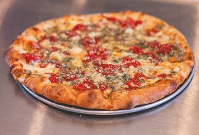 A Gorgonzola Special pizza with Roma tomato, roasted garlic and gorgonzola on a round tray, from the side