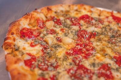 A close, soft focus look at a Gorgonzola Special pizza with Roma tomato and gorgonzola