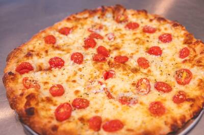 A close look at a Greek pizza with tomatoes and herbs over melted cheese