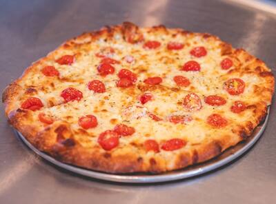 A Greek pizza with tomatoes and herbs, from a slightly different angle