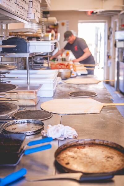 The kitchen make line with peels and pans and a cook working at the far end