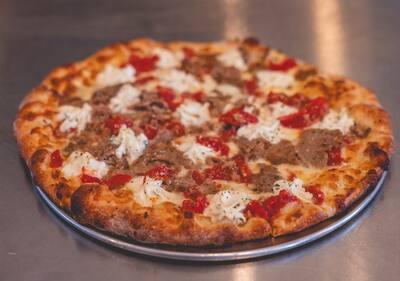 A Meatball Parm pizza with crumbled meatball, Roma tomato and spoonfuls of ricotta