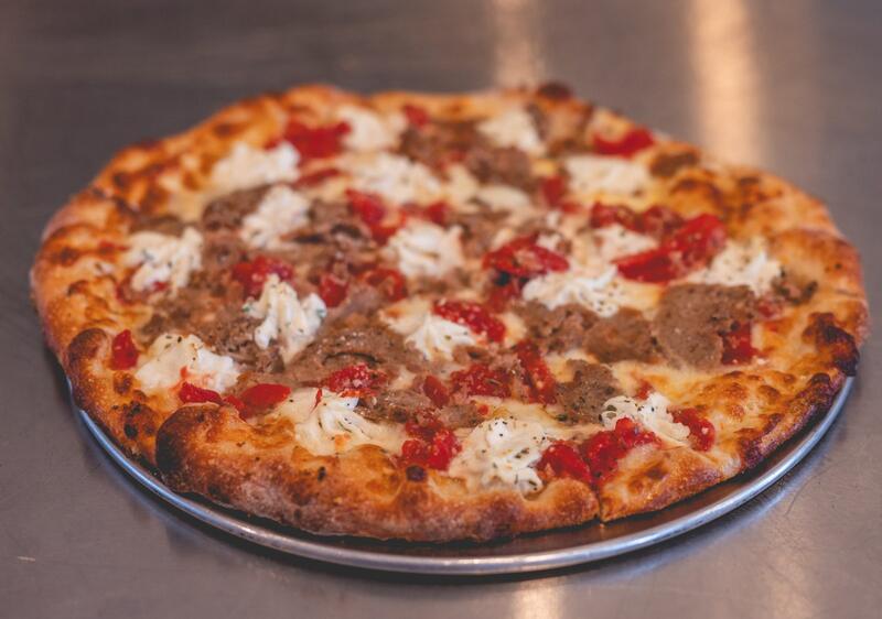 A Meatball Parm pizza with crumbled meatball, Roma tomato and spoonfuls of ricotta