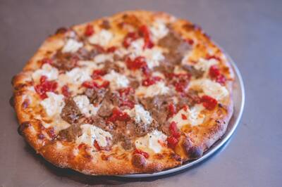 A Meatball Parm pizza with crumbled meatball, Roma tomato and ricotta, seen from above