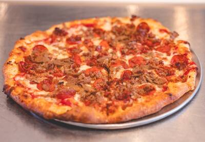 A Meatlovers pizza with pepperoni and crumbled sausage, close to the camera