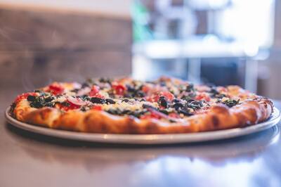 A Mediterranean pizza with spinach, black olives, tomatoes and feta, shot low across the counter
