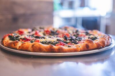 A low angle look at a Mediterranean pizza with spinach, black olives, tomatoes and feta