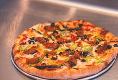 A Mom's Veggie pizza with eggplant, green peppers and black olives, seen at an angle
