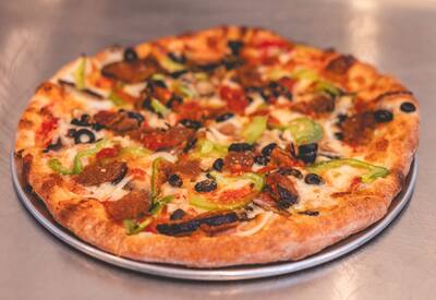 A Mom's Veggie pizza with eggplant, green peppers and black olives on a round tray