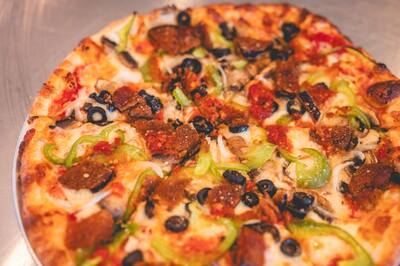 A close look at a Mom's Veggie pizza with eggplant, green peppers and black olives