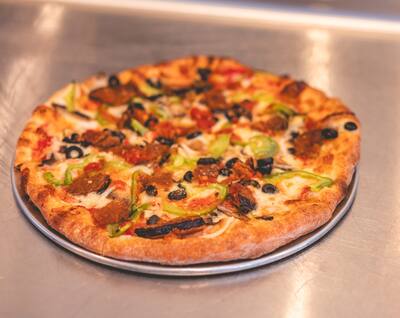 A Mom's Veggie pizza with eggplant, green peppers and black olives, from the side