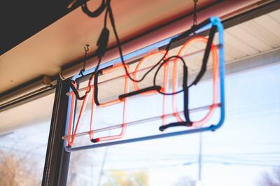 A blue and orange neon sign hanging in the shop window