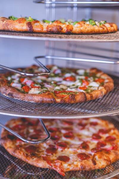 Three pizzas on a tiered wire rack, close up