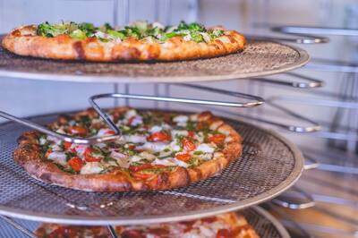 Pizzas with broccoli, tomato and pepperoni on a tiered wire rack