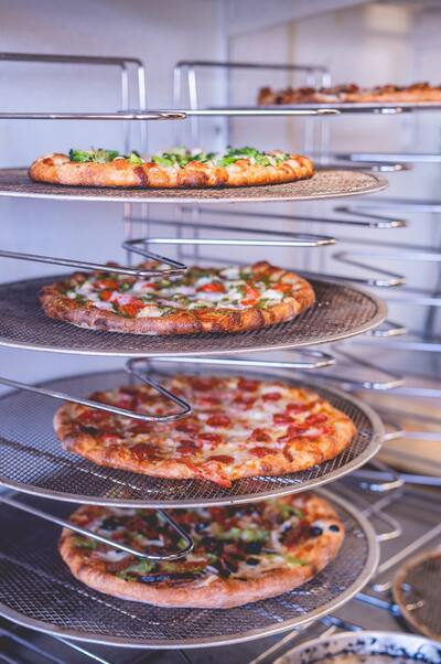 Pizzas with broccoli, tomato and pepperoni on a tiered wire rack