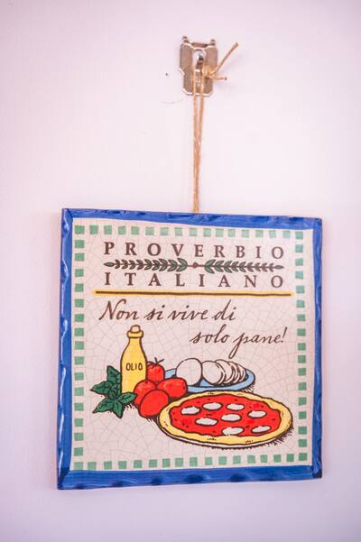 A tile on the wall with an Italian saying and a pizza