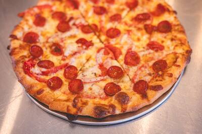 A Rhody Ram pizza with pepperoni and sliced tomato on a white pie with no red sauce