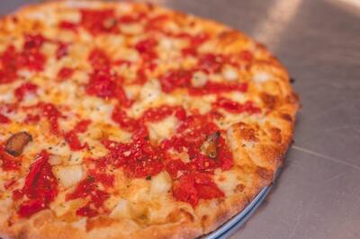 A close look at a Roma and Garlic pizza with chopped roasted tomatoes and garlic