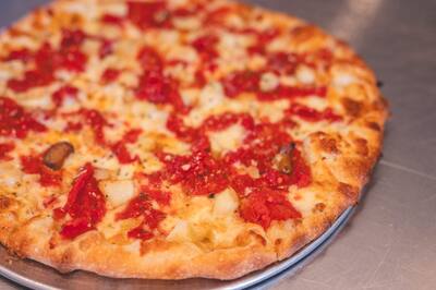 A Roma and Garlic pizza with chopped roasted tomatoes and garlic, close to the camera
