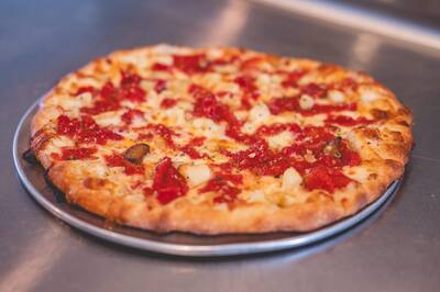 A Roma and Garlic pizza with chopped roasted tomatoes and garlic on a steel counter