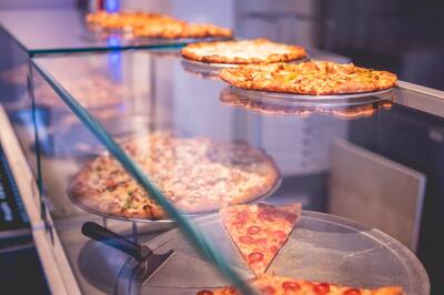 Pies lined up on stands behind the glass of the slice case
