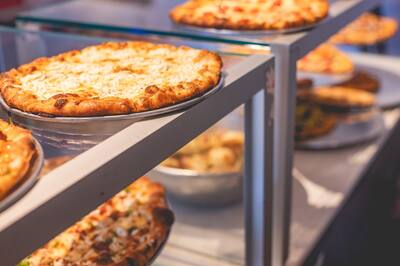 Pizzas and garlic knots on the shelves of the slice case