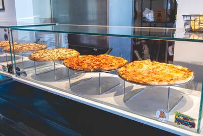 The slice case with whole pies on stands behind glass