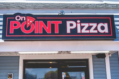 The red and black On Point Pizza sign over the door