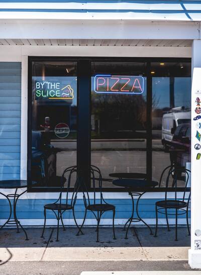 The shop window with neon signs and bistro chairs out front
