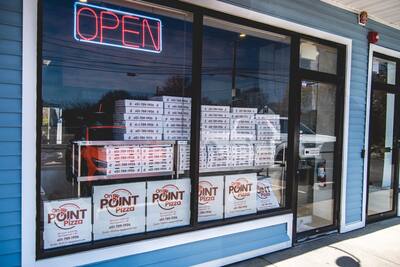 The shop window with an open sign and stacks of pizza boxes
